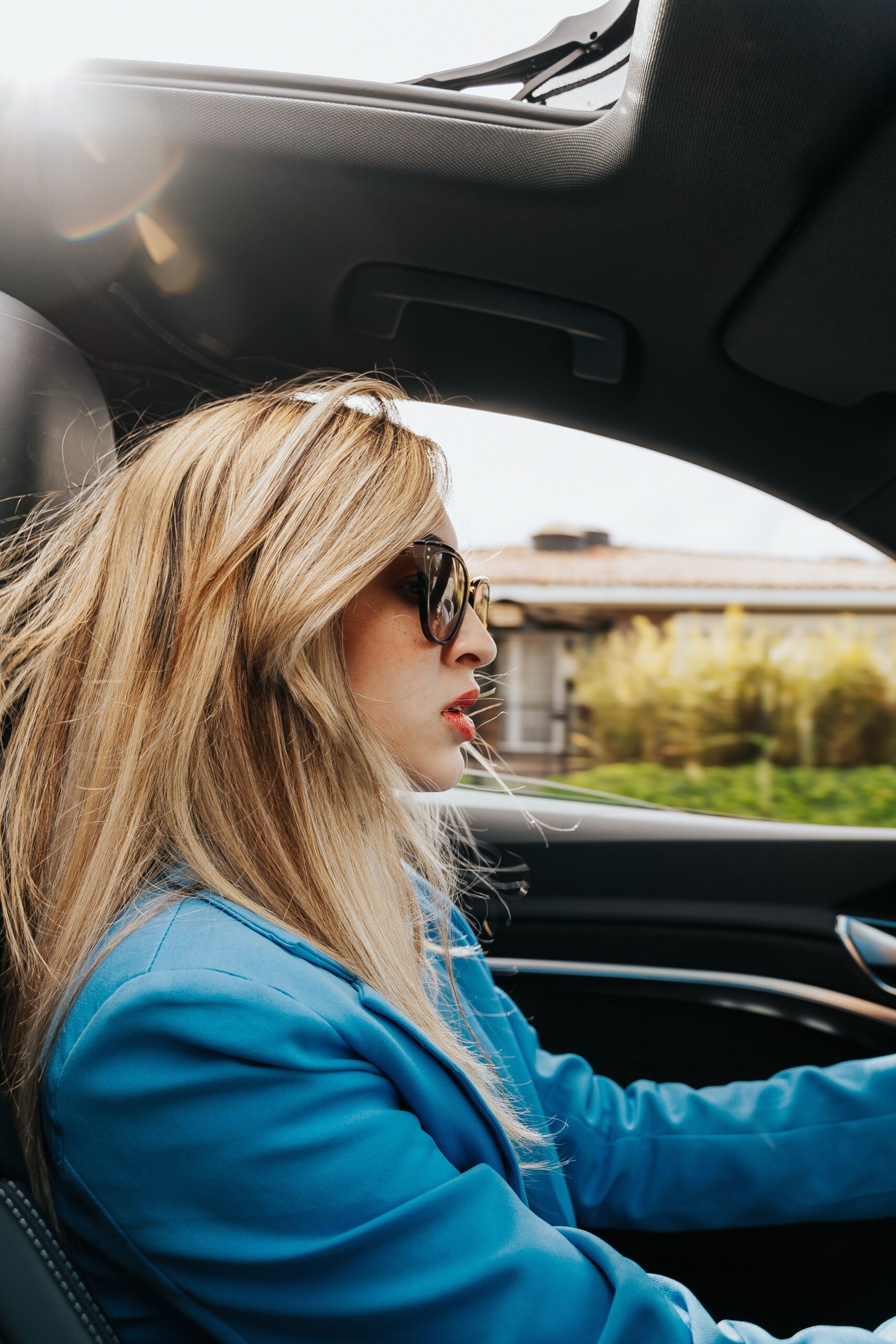 Fashionable young woman driving a car in Curitiba, Brasil, wearing sunglasses.